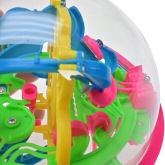 Boule de jeu Addict A Ball avec un design coloré, composée de pièces en plastique jaune, vert, bleu et rose, à l'intérieur d'un dôme transparent. Le mécanisme complexe présente des tunnels et des obstacles pour faire rouler une petite bille.