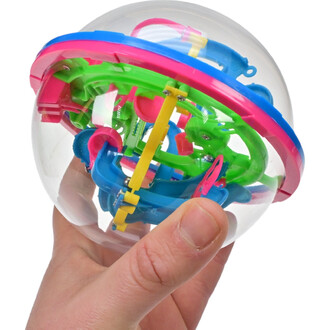 Main tenant un jouet en forme de sphère transparente avec des éléments de jeu colorés à l'intérieur. Les pièces internes sont disposées en mécanismes de jeu comprenant des composants verts, bleus, jaunes et roses.