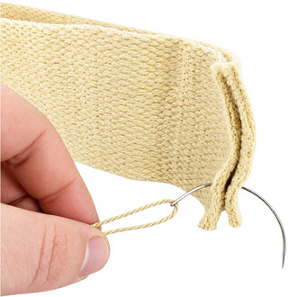 Plan rapproché d'une aiguille incurvée avec fil Kevlar beige tenu par une main, prêt à l'assemblage.