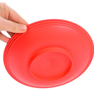 Assiette chinoise rouge de jonglerie, vue de dessous, maintenue par une main. La surface est lisse et arrondie avec un design simple.