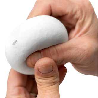 Main tenant une balle BBX Beanbag de couleur blanche, légèrement déformée par la pression des doigts. La balle présente une texture douce et un petit orifice sur un côté.