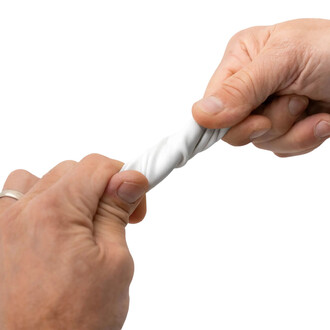 Deux mains serrent une balle BBX Beanbag de Play, la déformant en la tordant. La balle est principalement de couleur blanche et présente une texture douce. L'arrière-plan est neutre pour mettre en valeur le produit.