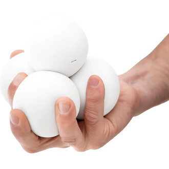 Main tenant quatre balles blanches en forme de boule, avec une texture lisse, représentant la balle BBX Beanbag de Play.