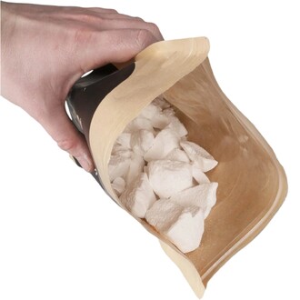 Main tenant un sachet souple de magnésie en vrac Getta Grip 200 g, ouvert, montrant des morceaux blancs dans le sac transparent.