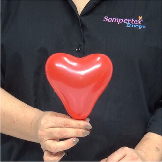 Personne tenant un ballon en forme de cœur rouge brillant près du torse, vêtue d'une chemise noire avec le logo Sempertex Europe.