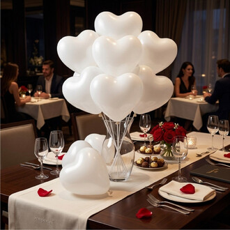 Centre de table décoratif avec des ballons blancs en forme de cœur regroupés dans un vase transparent, ambiance dîner romantique.