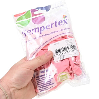 Paquet de ballons cœur roses, 50 ballons emballés dans un sachet transparent avec étiquette et code-barres, tenu par une main.