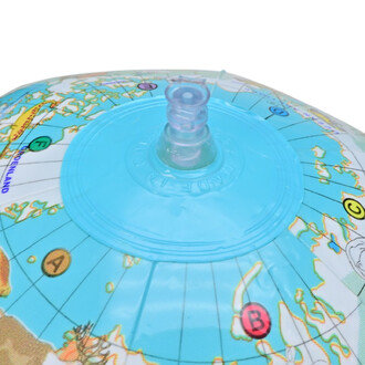 Ballon globe représentant une carte du monde, avec une valve bleue sur le dessus pour le gonflage, détails colorés des continents et des océans visibles.
