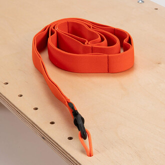 L'image montre une longue laisse de couleur orange enroulée sur une surface en bois clair. La laisse est fabriquée dans un matériau souple et présente un clip noir à une extrémité pour attacher à un objet.