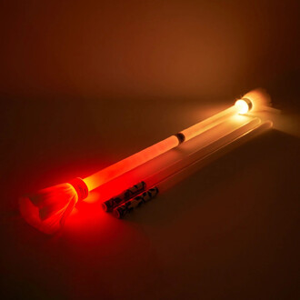 Bâton du Diable Lumi Pro de Trickstix, composé de trois bâtons lumineux. Un bâton émet une lumière rouge tandis qu'un autre diffuse une lumière orange. Le design est minimaliste avec des motifs sur les extrémités. Les bâtons sont posés sur une surface som