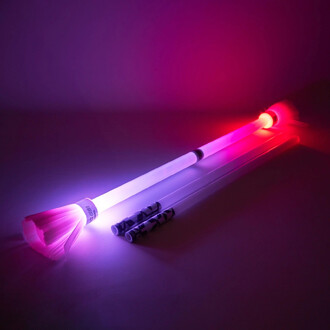 Bâton du Diable Lumi Pro de Trickstix avec des extrémités lumineuses, émettant des couleurs violettes et rouges, posé sur une surface sombre, avec deux bâtons supplémentaires à côté.