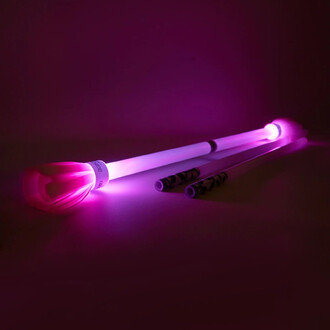 Bâton du Diable Lumi Pro - Trickstix, éclairé en violet, avec une tige blanche et des embouts lumineux, posé sur un fond sombre.