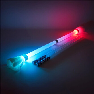 Bâton du Diable Lumi Pro de Trickstix avec un embout lumineux bleu et rouge, posé sur une surface neutre. Le bâton est accompagné de deux tiges de jonglage transparentes. Éclairage ambiant subtil.