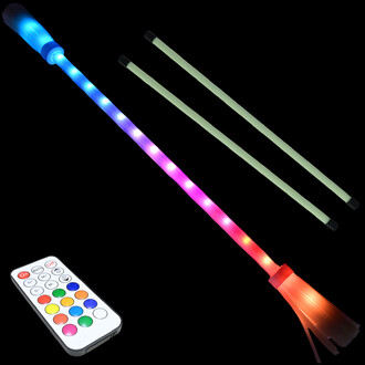 Bâton de fleur lumineux avec des lumières LED multicolores, accompagné de deux bâtons supplémentaires. On voit également une télécommande pour contrôler les lumières. Fond noir.