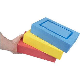 Main tenant un bloc rouge en mousse avec deux blocs jaune et bleu empilés au-dessus; le bloc bleu supérieur présente une rainure rectangulaire sur son dessus.