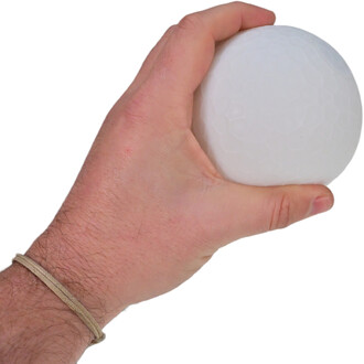 Main tenant une boule de jonglerie blanche, texture hexagonale visible, avec un bracelet en cordon autour du poignet.