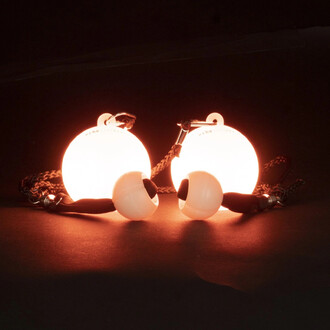 Bolas LED Echo Orbit de Firetoys, composées de deux boules lumineuses blanches, suspendues par des cordes. Les boules émettent une lueur orange sur un fond sombre, avec des poignées en mousse noire.