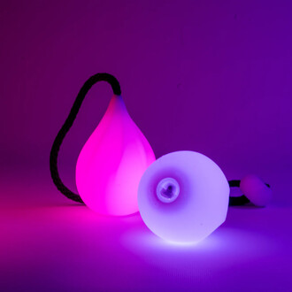 Bolas lumineuses de jonglerie avec une finition en silicone, l'une en forme de goutte, émettant une lumière rose, et l'autre de forme ronde, émettant une lumière bleue, sur un fond violet.