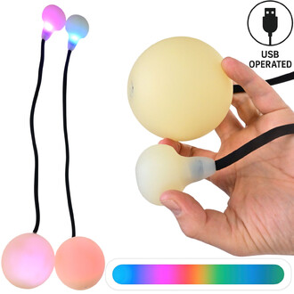 Bolas lumineuses Supernova, montrant deux bolas suspendues avec une lumière multicolore à leurs extrémités et une bola tenue dans une main. Les bolas ont une finition douce et sont connectées par des cordons noirs. Inclus également un élément graphique in
