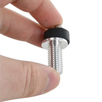 Boulon Fusion 1.0 Threeworlds (ancienne version) en gros plan : tige filetée argentée tenue entre le pouce et l’index, avec bague noire et petite molette métallique sur le dessus.