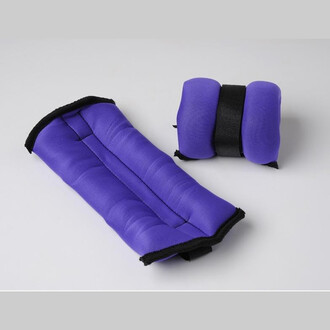 Due braccialetti di schiuma viola con pesi e cinturini neri, uno lungo e imbottito e l'altro corto e compatto, pensati per l'allenamento.