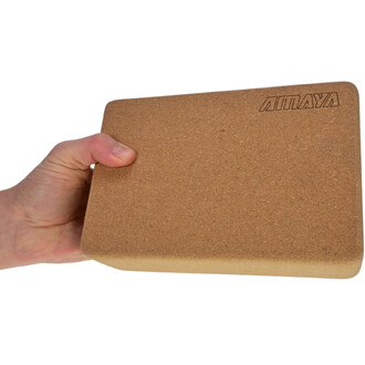 Brique de yoga en liège tenue à la main, montrant une surface lisse et naturelle, avec le logo AMAYA gravé sur l'un des côtés.