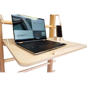 Ordinateur portable sur un bureau en bois clair, avec un écran affichant des informations. À côté, un smartphone est posé sur un support en bois. Un petit réglet est visible sur le bord du bureau.