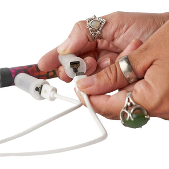 Gros plan sur une main qui branche le câble Lumi Pro double alimentation blanc; le connecteur USB‑C est visible.