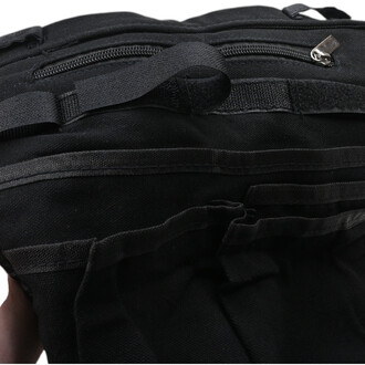 Gros plan sur une ceinture tablier ballon noire en tissu robuste avec fermeture éclair métallique et sangles de fixation.