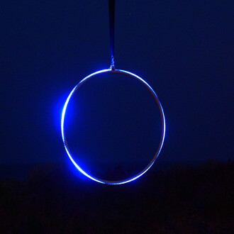 Cercle lumineux bleu suspendu dans un environnement nocturne, visible de profil.