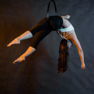 Acrobate réalisant une pose aérienne élégante sur un cerceau noir de 50 cm, idéal pour les performances aériennes artistiques.