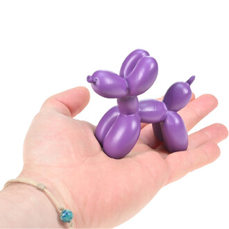 Chien en ballon violet, décoration ballon animal tenu dans la main sur fond blanc.