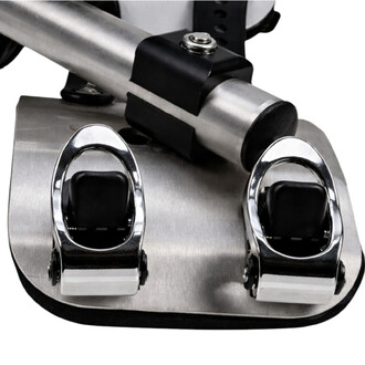 Détail d’un socle métallique avec deux étriers chromés en forme de boucle et patins noirs, fixés sur une plaque argentée.