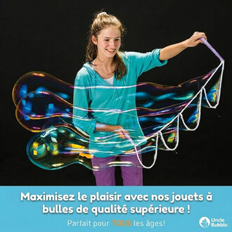 Jeune femme souriante faisant de grandes bulles colorées avec une baguette à bulles sur fond noir (publicité Uncle Bubble).