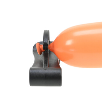 Détail d’un coupe-ballons noir en métal avec un ballon orange inséré dans le mécanisme de coupe.
