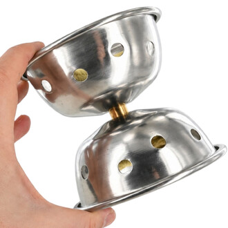Diabolo de Feu NetJuggler en acier inoxydable avec moyeu central doré, maintenu par une main, montrant les coupelles percées de trous de ventilation.