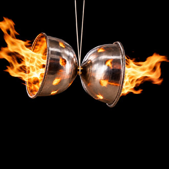 Diabolo de Feu NetJuggler en métal argenté avec flammes s'échappant des deux côtés, tenu par des baguettes, sur fond noir.
