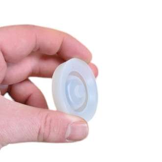 Embout haut massue Vision en plastique translucide blanche, disque circulaire avec bossage central, tenu entre le pouce et l'index.