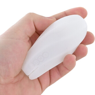 Gros plan d’un embout blanc oval en plastique, tenu entre le pouce et l’index d’une main.