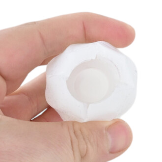 Petit embout en plastique blanc, cylindrique et creux, avec une ouverture centrale, tenu entre le pouce et l’index.