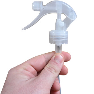 Embout spray transparent avec gâchette, tenu entre les doigts, destiné au désodorisant mascottes.