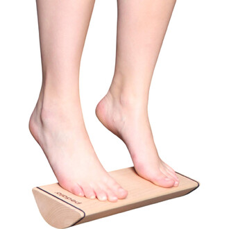 Deux pieds nus se tiennent sur une plateforme en bois, légèrement inclinée. La surface de la plateforme est lisse et présente un design épuré. L'image met en avant la texture et la couleur naturelle du bois, avec une ligne noire qui délimite les bords.