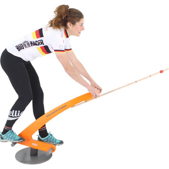 Femme en tenue de sport effectuant un exercice avec un trainer visuel pour vélo, tenant une barre orange avec une boule rouge à l'extrémité, en équilibre sur une base ronde.