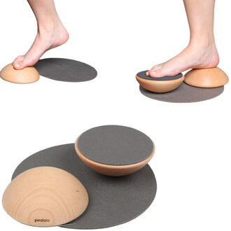 Deux accessoires en bois sur un tapis antidérapant, avec des pieds posés dessus. L'un est une demi-sphère et l'autre est un bol, tous deux en bois clair, servant à des exercices d'équilibre.