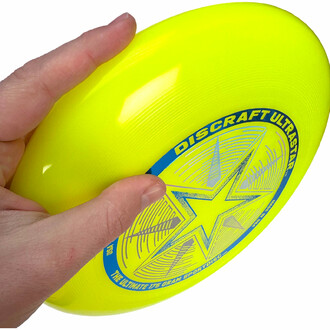 Frisbee jaune tenu dans la main prêt à être lancé.