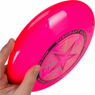 Frisbee rose tenu dans la main prêt à être lancé.
