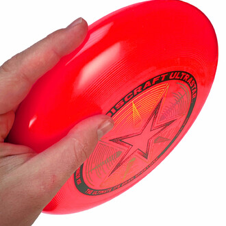 Frisbee rouge tenu dans la main prêt à être lancé.