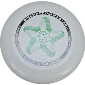 Frisbee Discraft Ultrastar phosphorescent de couleur blanche avec un design central représentant un symbole d'étoile entouré d'une grille. Le texte DISCRAFT ULTRASTAR est inscrit en haut, et THE ULTIMATE 175 GRAM SPORTDISC est visible en bas, tandis que M