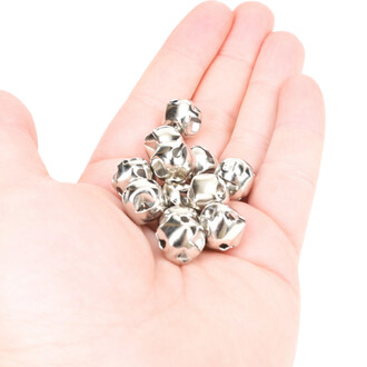 Grelots en métal argenté de 12 mm, présentés dans une main, avec une fente croisée visible sur chaque grelot.