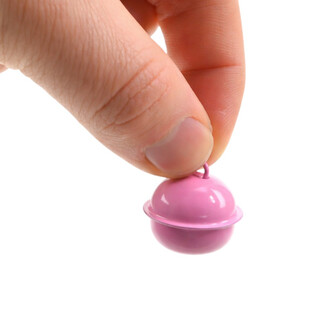 Grelot plat de 22 mm de couleur rose, tenu entre le pouce et l'index d'une main. Le grelot a une forme sphérique avec une finition brillante.